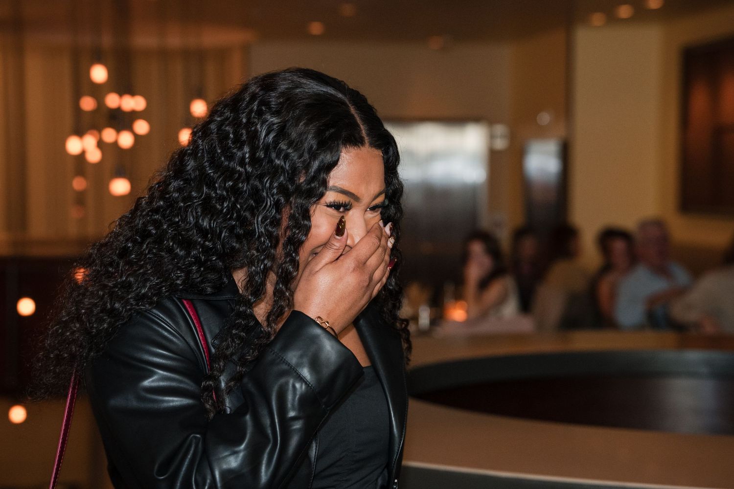 A couple shares an intimate moment at an indoor reception venue with warm lighting and bokeh effects in the background.