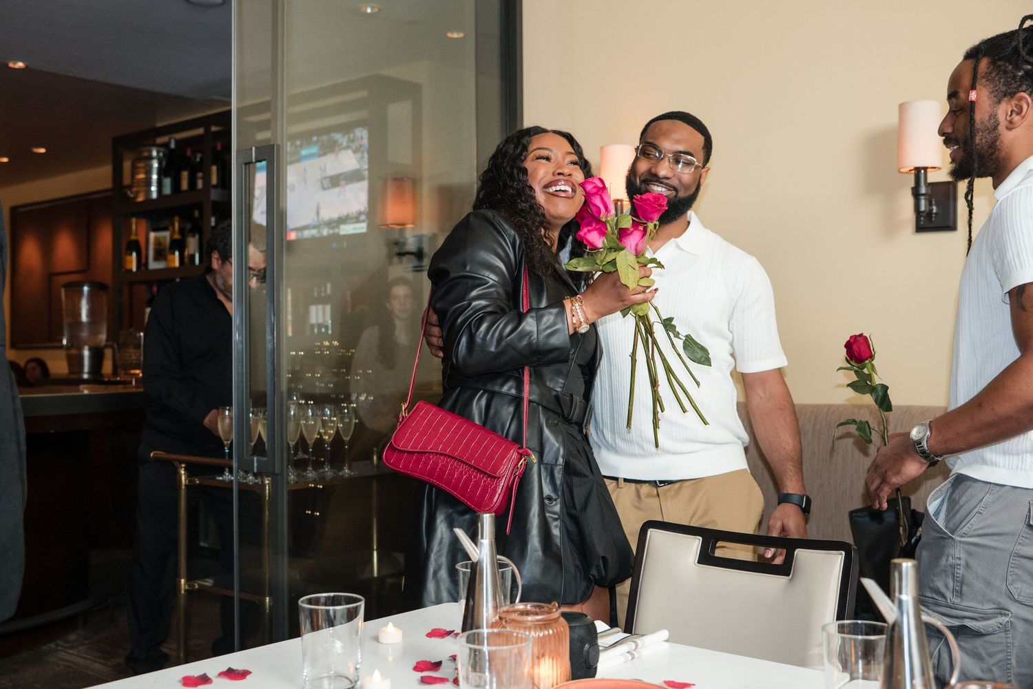 Joyful celebration moment at an indoor restaurant with roses and decorative table settings.