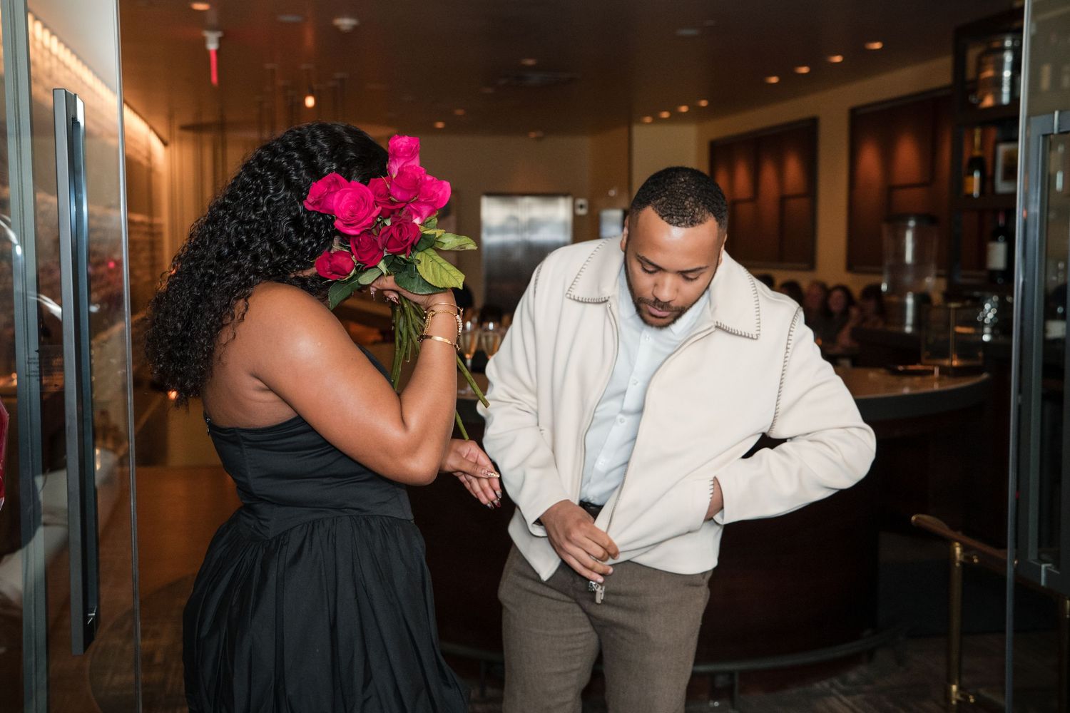 Couple sharing an intimate moment in a restaurant with romantic lighting and roses.