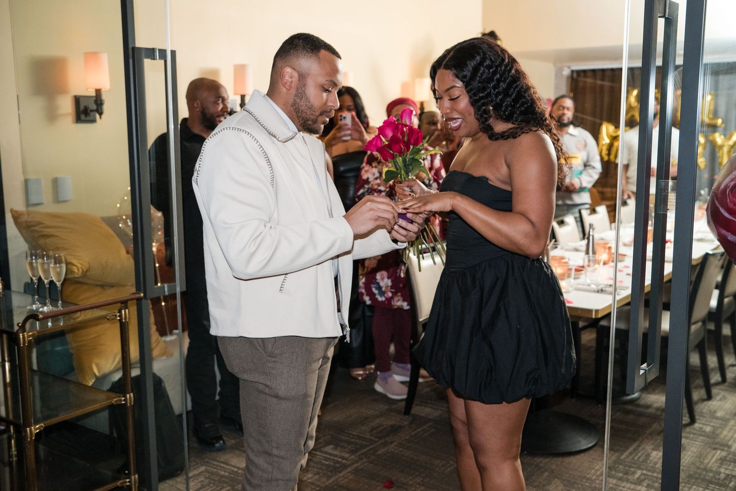 A surprise proposal moment captured at an indoor venue with onlookers in the background.