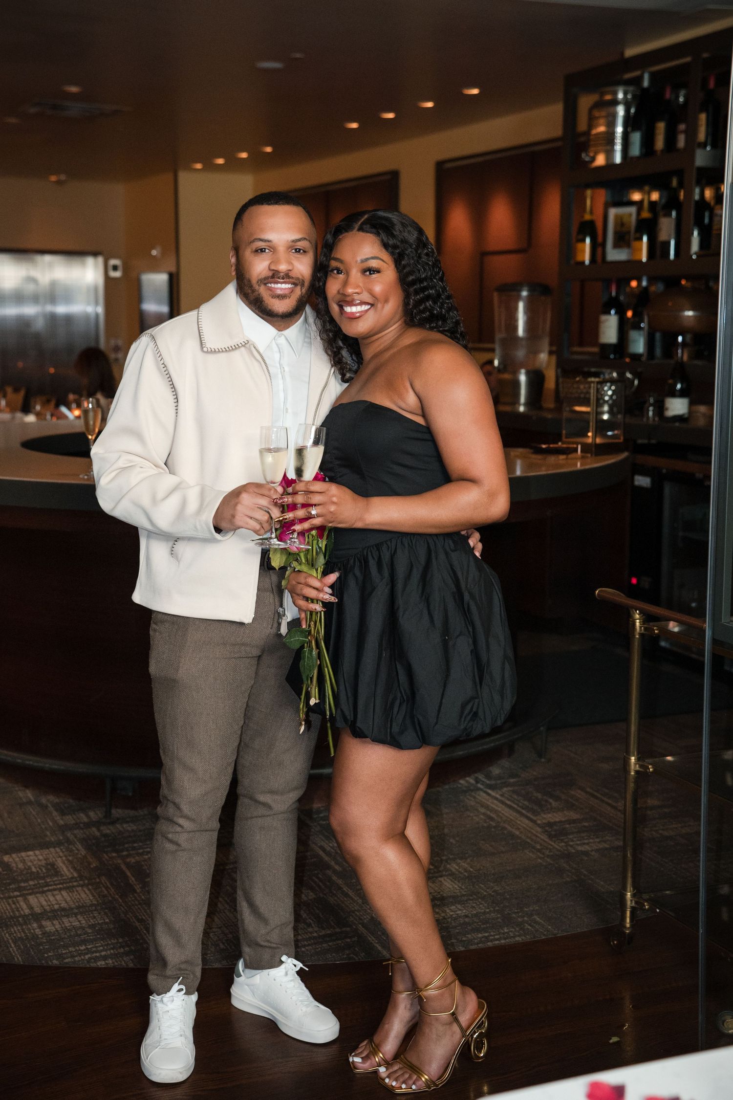 A couple sharing a romantic moment in a stylish restaurant bar area with modern lighting.