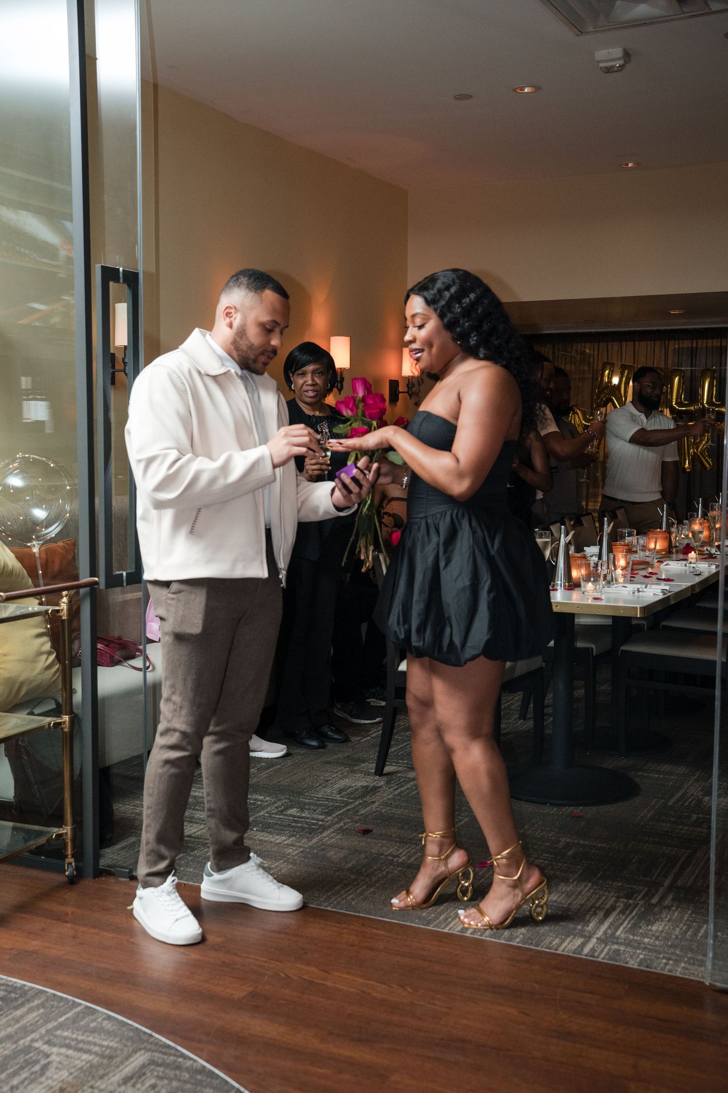 A proposal scene unfolds in an indoor venue with decorative lighting and hardwood floors.