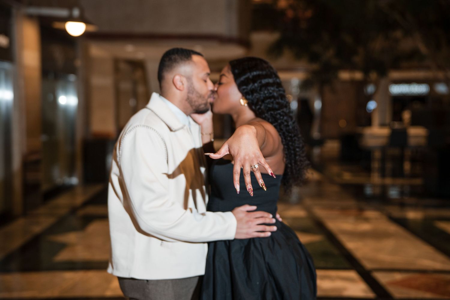 Couple sharing intimate moments during nighttime photo session in modern building interior.