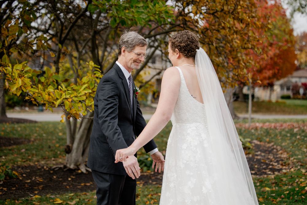 Newlyweds share romantic moments together during an autumn photoshoot with colorful fall foliage in the background.
