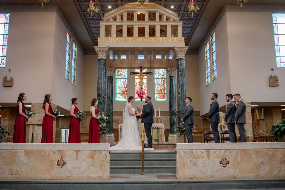 Wedding party members stand in a line with arms raised in celebration at a church ceremony.