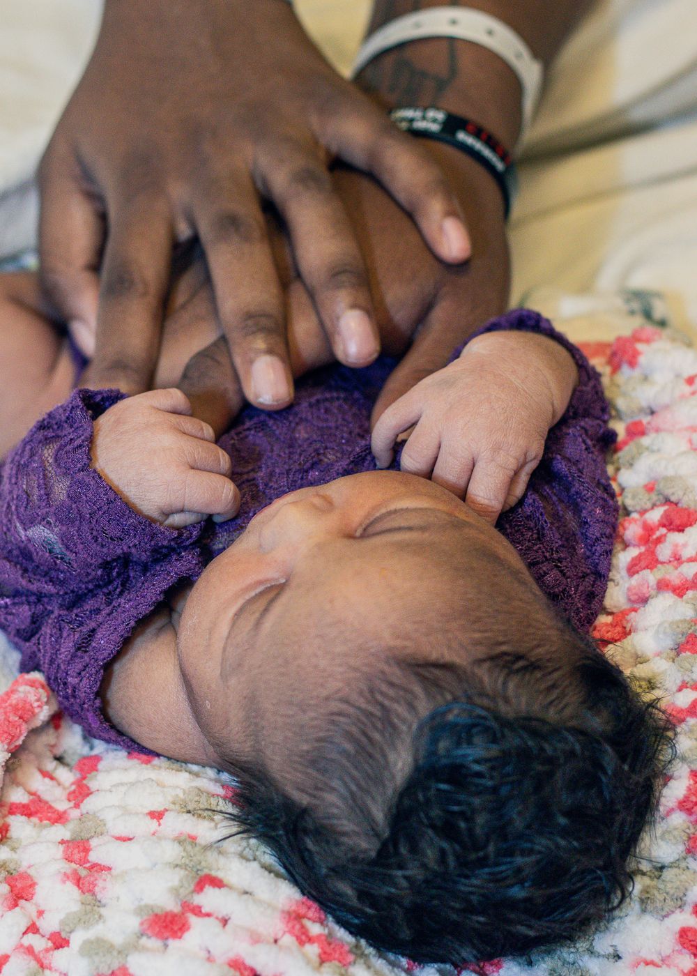 Tender close-up shots of a newborn baby wearing purple lace against floral bedding.