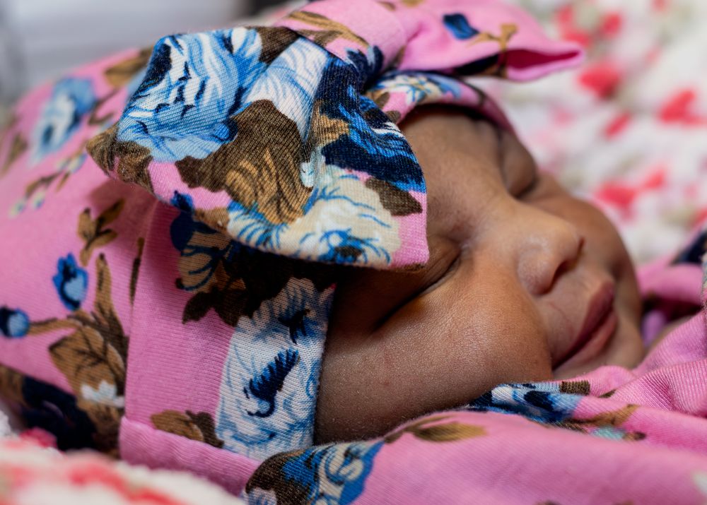 Peaceful sleeping baby in pink with a blue floral headband.