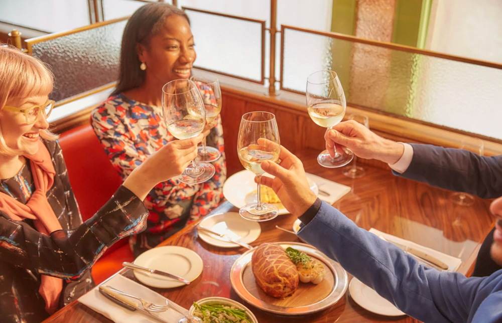 Group dining together at restaurant table with food and drinks.