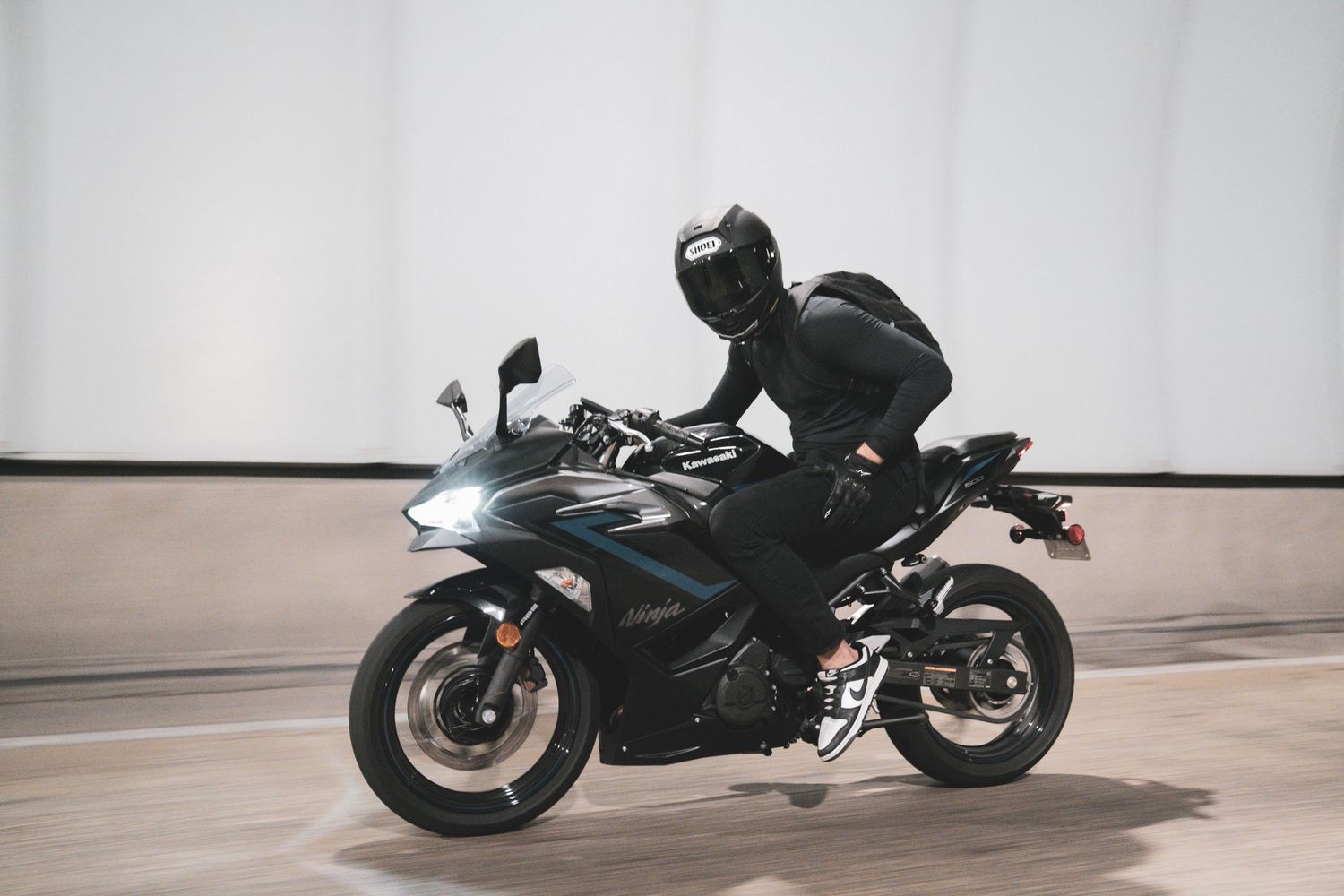 A series of dynamic motorcycle shots showing a black sports bike in different riding positions against a light background.