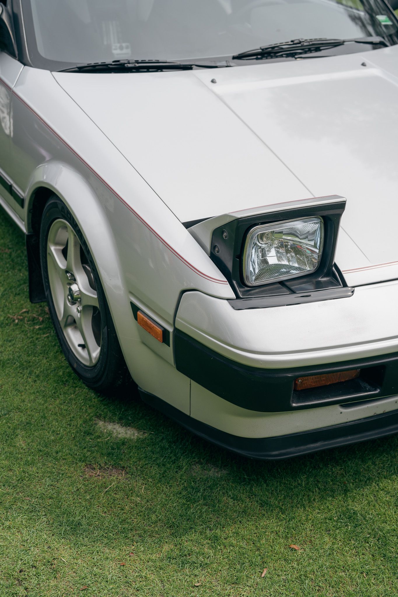 Close-up views of a white Ferrari F40's front end showing the iconic pop-up headlights and aerodynamic design.