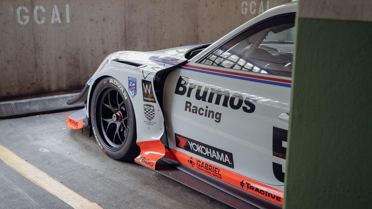 A row of vintage Porsche 911 racing cars with Martini Racing livery parked in a garage.