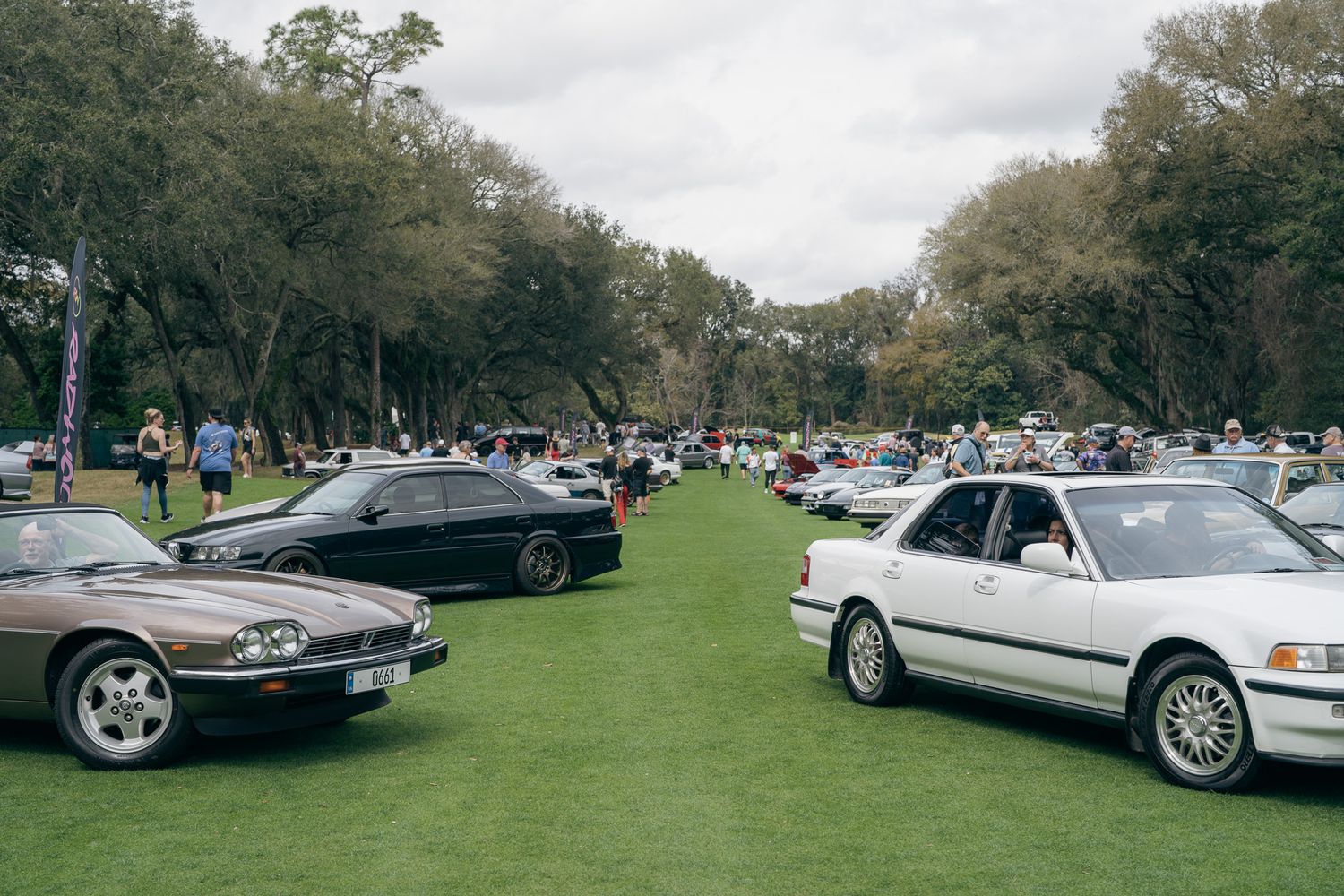 A panoramic view of classic luxury cars lined up on display at an outdoor car show event.