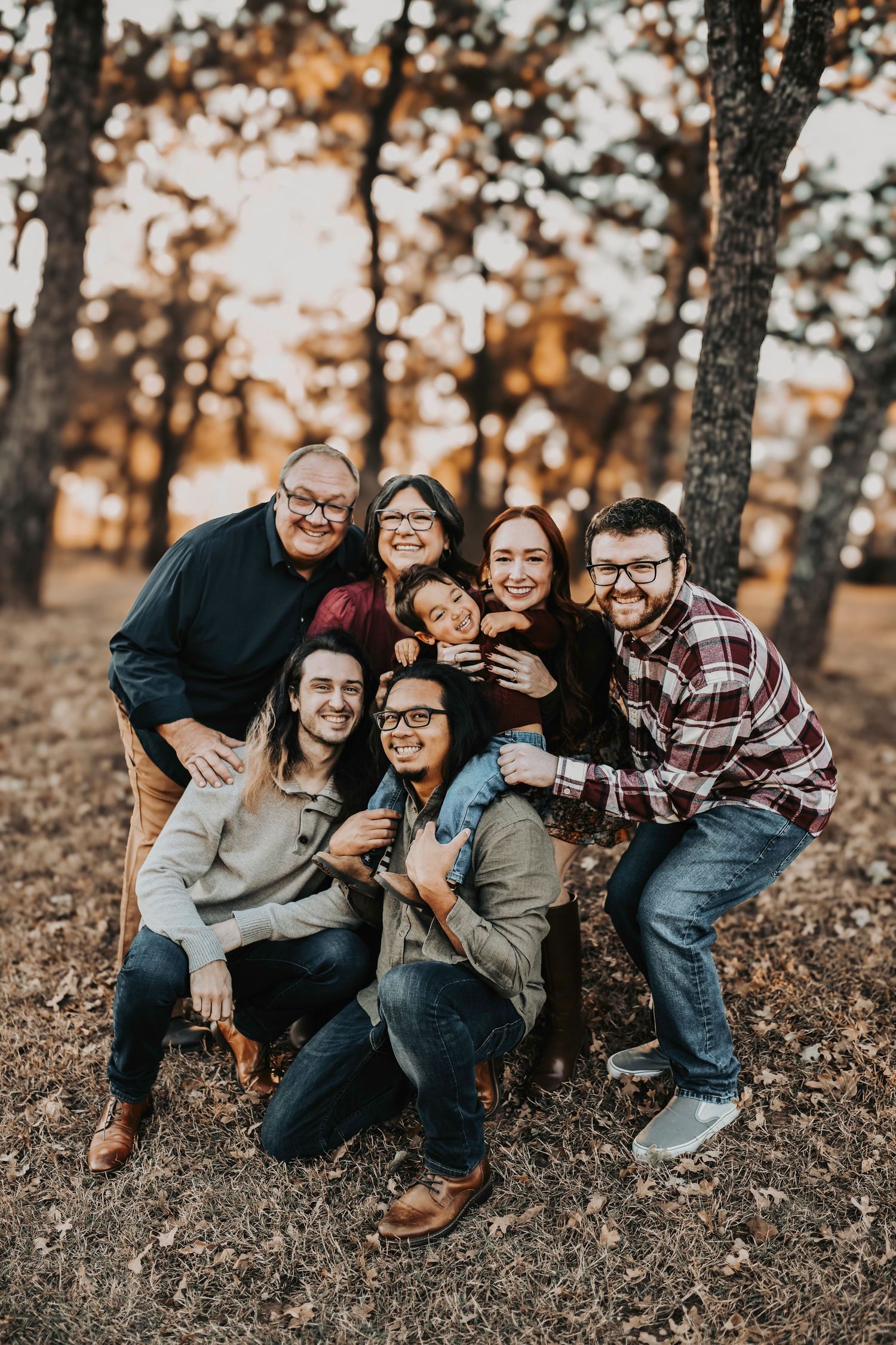 Multi-generational fall family photo surrounded by golden leaves in a Texas forest.