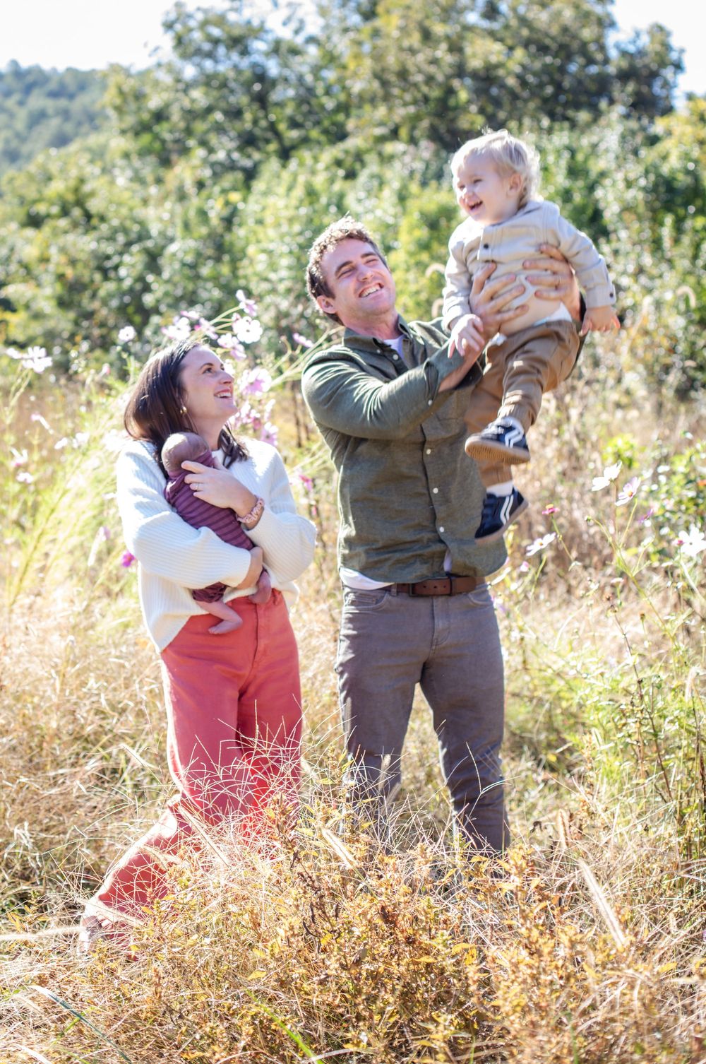 A joyful moment captured in a sunlit field with tall grass during golden hour.