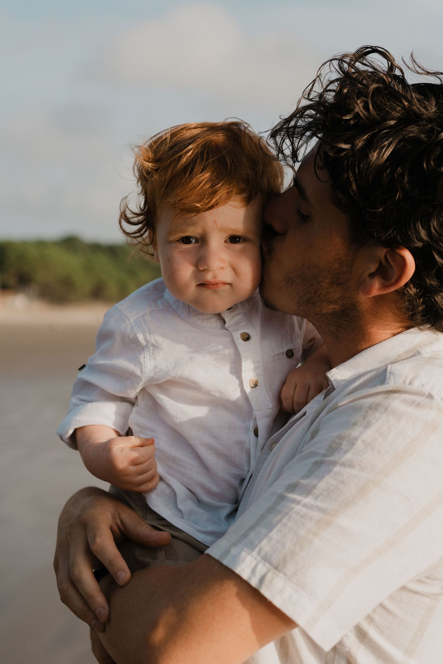Bisou tendre d'un papa sur la joue et son fils, sur la plage.