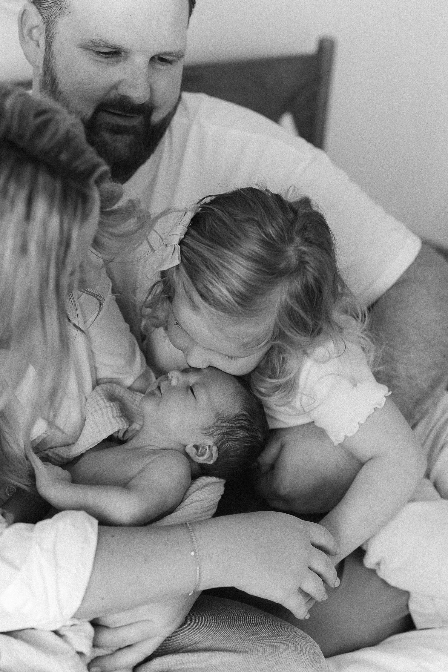 Sweet family newborn photos featuring parents and a sibling gathered around their newborn in Orange County