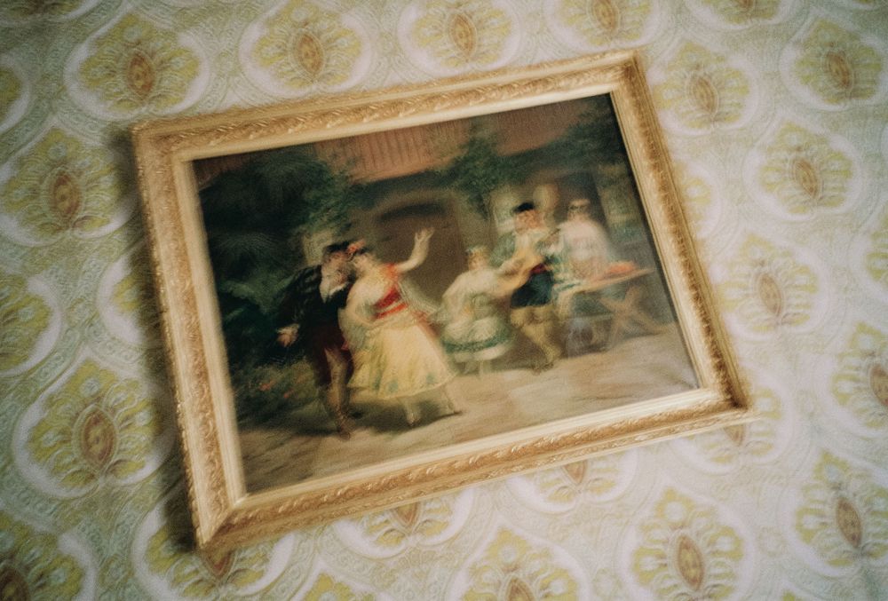 Series of vintage-style framed artworks hanging on ornate wallpaper.