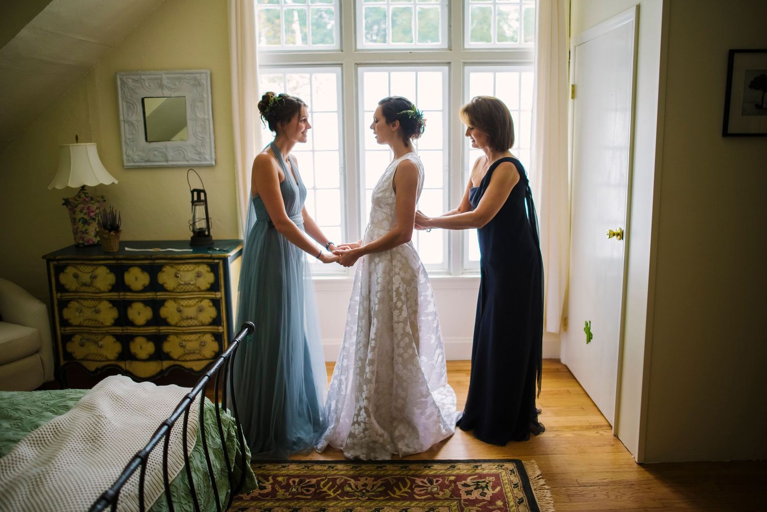 Natural light streams through windows as a wedding dress is showcased in an elegant room.