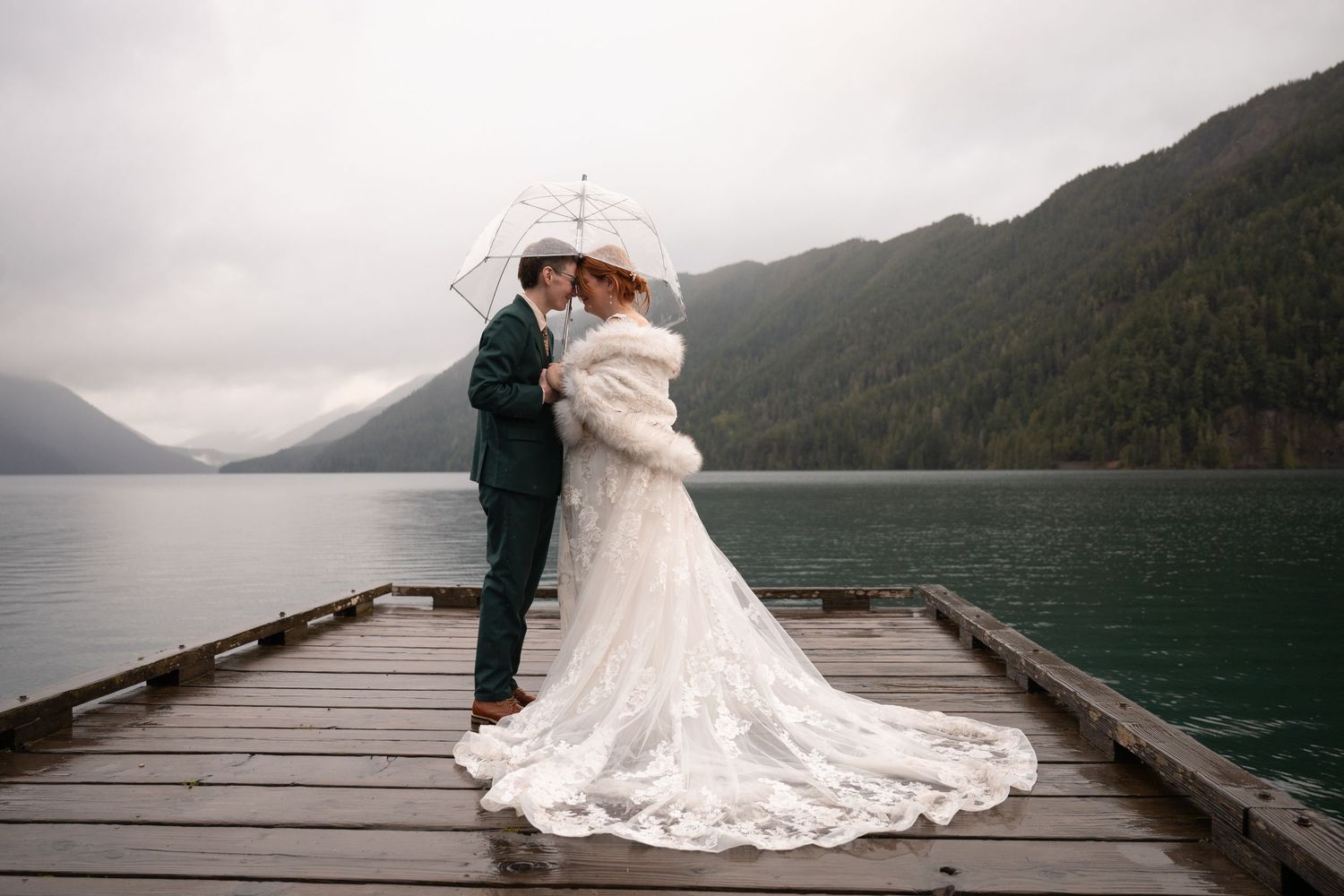 Two women embrace each other on a dock on Lake Crescent in Olympic National Park, celebrating their Pacific Northwest adventure elopement