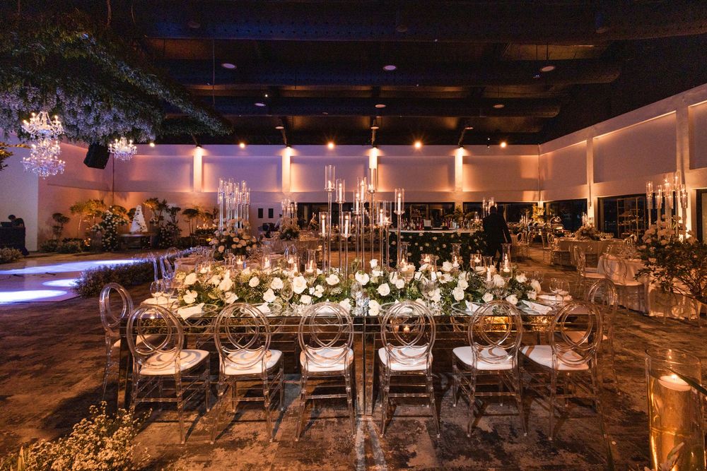 Elegant wedding reception venue with white floral centerpieces and warm candlelight creating a romantic atmosphere.