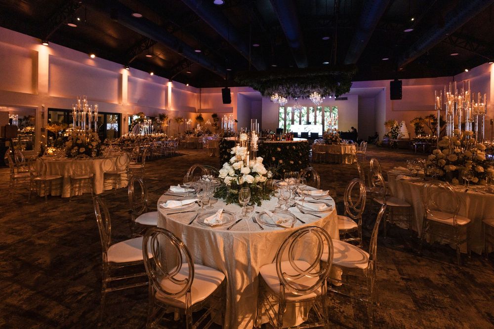 Elegant wedding reception venue with round tables set with white linens and romantic lighting for an evening celebration.