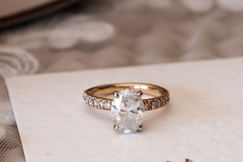 Elegant engagement ring with delicate diamond details sparkles against a soft white background.
