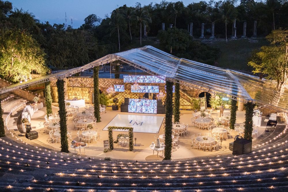 Rustic outdoor wedding venue illuminated with romantic string lights at dusk creating a magical atmosphere.