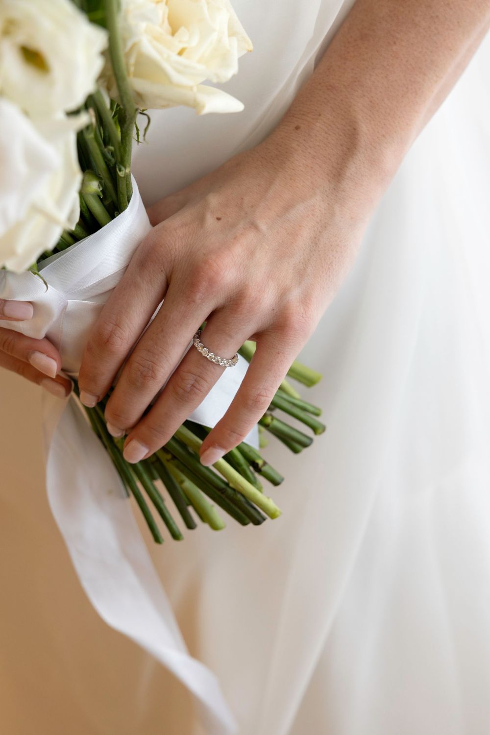 Close-up sequence showing hands adjusting and arranging a white floral bouquet with green stems.