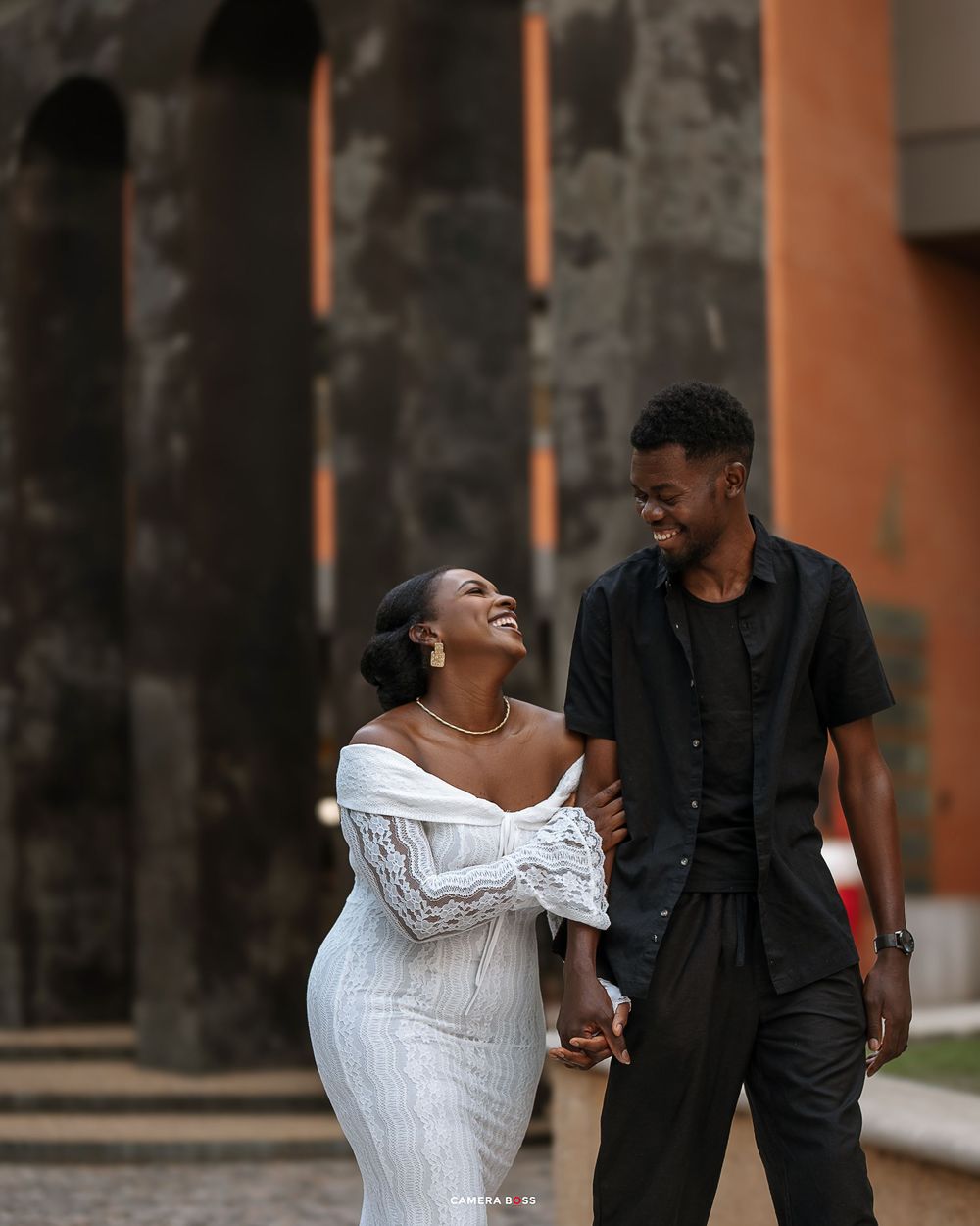 A couple in formal attire shares a joyful moment together while walking outdoors.