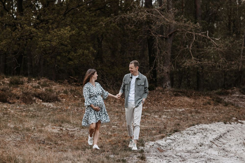 Couple holding hands while walking together on forest trail.