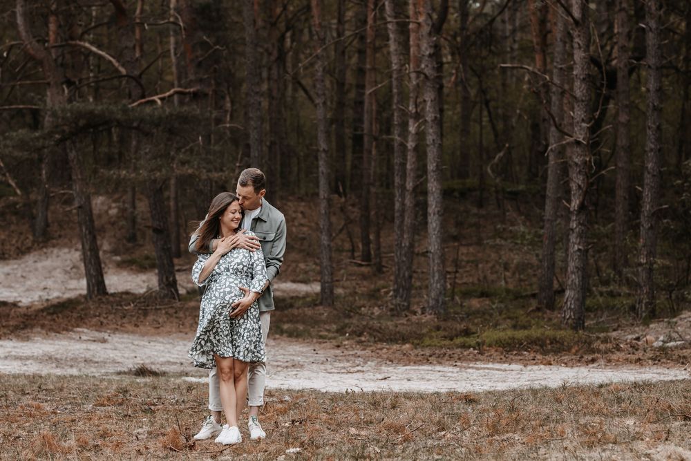 Romantic couple embracing on forest path during outdoor photoshoot.