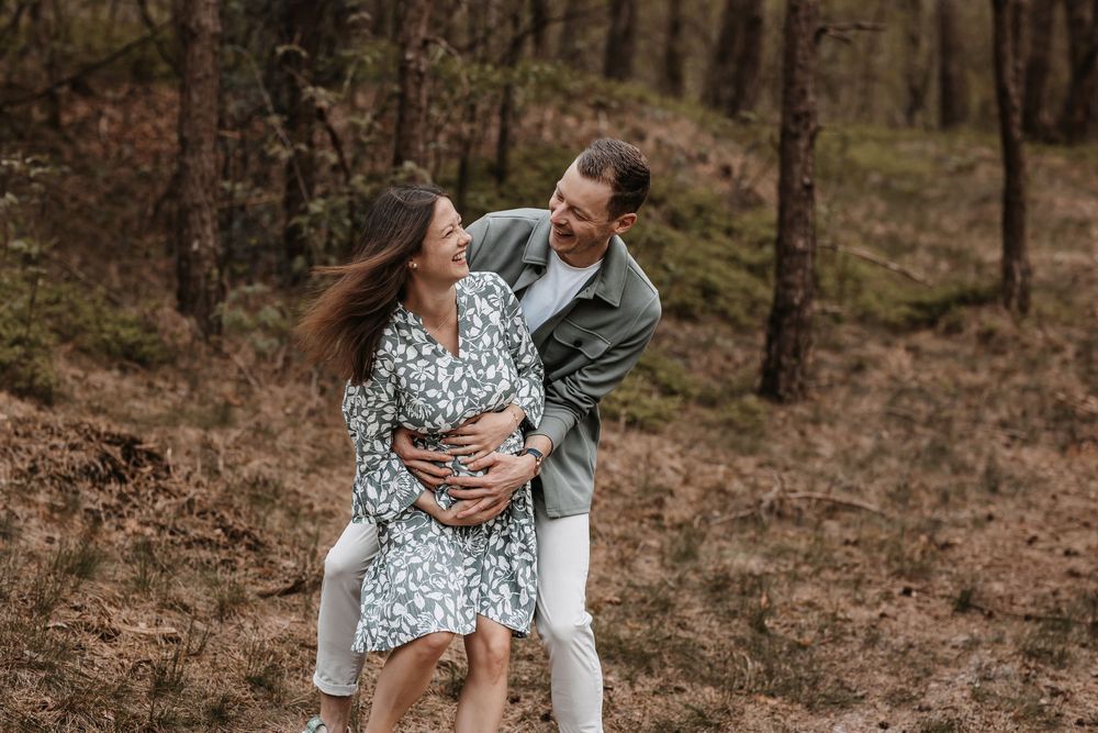 Romantic couple shares intimate moments during a woodland photoshoot with natural lighting.