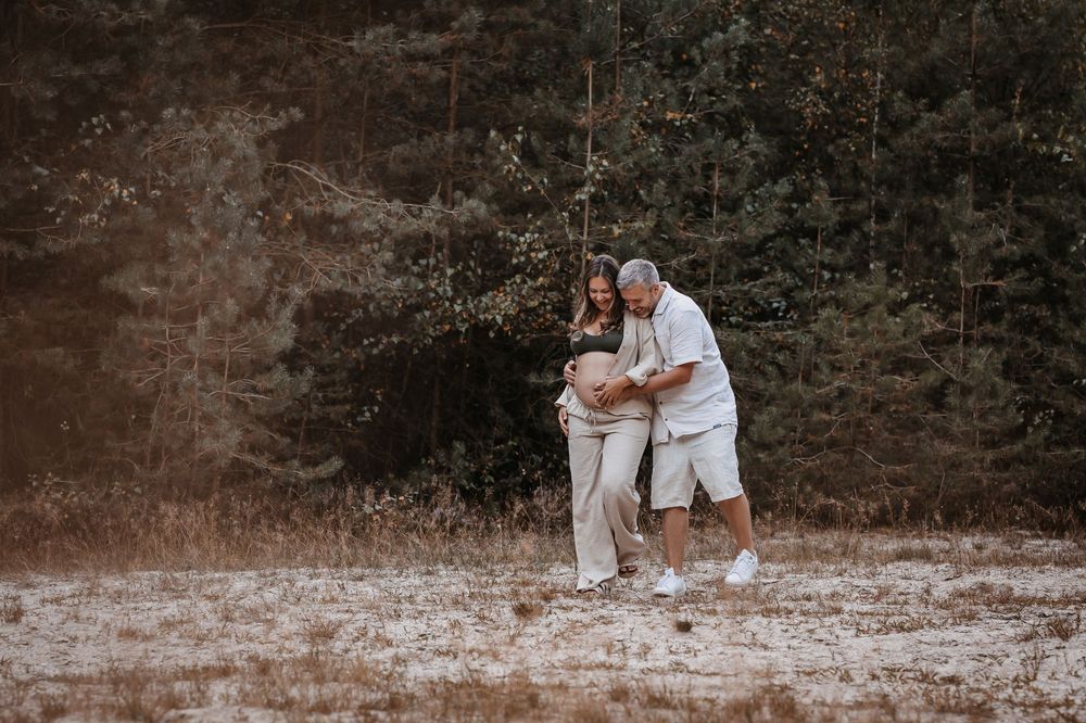 Couple embracing in a natural outdoor setting with autumn foliage.