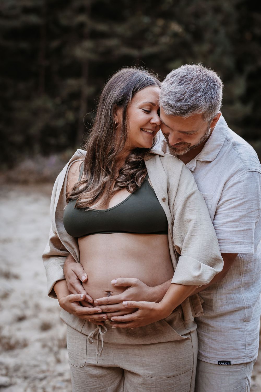 Intimate maternity photos showing loving embrace against natural backdrop.