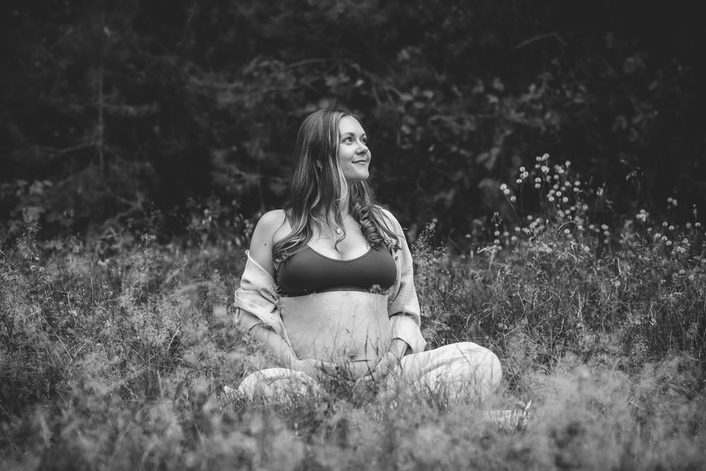 Black and white maternity photos in a field of wild grass.