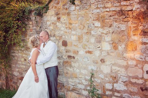 Golden hour capture of bride and groom against a beautiful stone wall in Northampton.