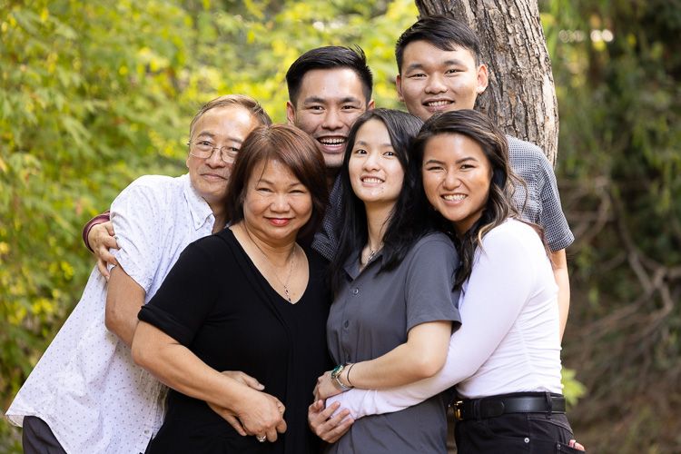 A Saratoga family smiles and embraces outdoors during their family photo session at golden hour