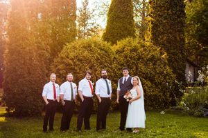 Wedding party poses together on a grassy hill during golden hour sunset.
