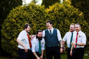 Wedding party members posing casually outdoors against green foliage background.