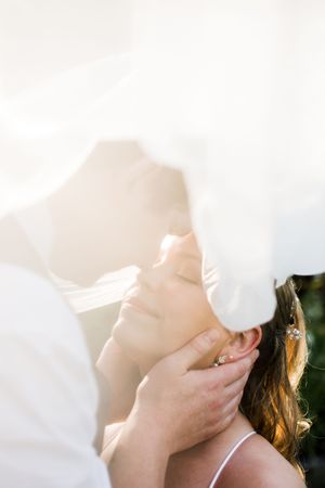 Romantic sunlit moment captured through soft white fabric creating an ethereal effect.