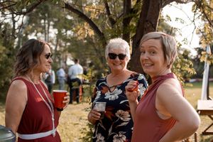 Wedding guests in burgundy dresses share joyful moments during outdoor celebration.