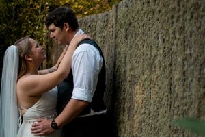 Wedding party members share candid moments against stone wall backdrop.