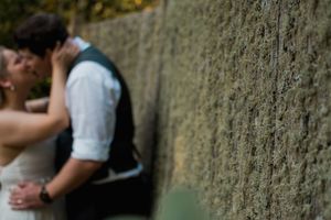 An intimate wedding moment captured against a rustic stone wall in soft focus.