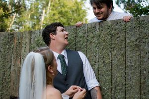 Groomsmen in vests and dress shirts share laughs during outdoor wedding festivities.