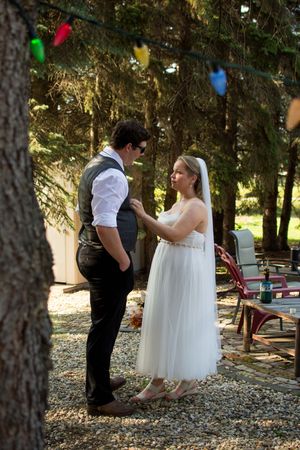 Couple shares a playful moment under trees decorated with colorful party lights.