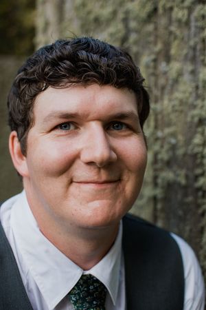 Close-up portrait of person in formal attire with black suit and tie.