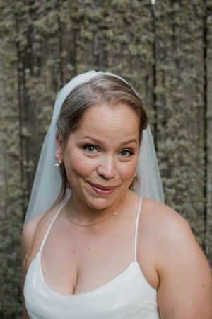 Bride wearing a white spaghetti strap dress and veil smiles playfully in a series of candid portrait shots.