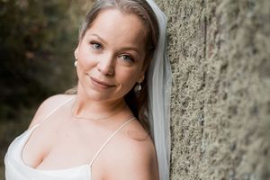 Close-up portrait against textured stone wall with soft natural lighting.