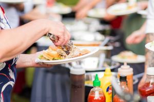 Wedding reception buffet line with guests serving food on plates.