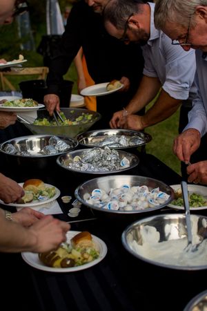 Buffet table at outdoor wedding reception with plates of food being served.